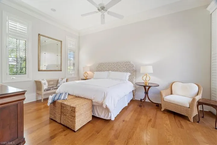 Bedroom with light wood-style flooring, multiple windows, and ornamental molding