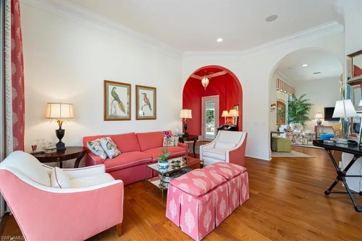 Living area with arched walkways, ornamental molding, wood finished floors, and recessed lighting