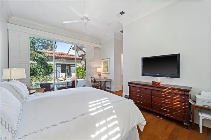 Bedroom featuring ceiling fan, wood finished floors, visible vents, access to exterior, and crown molding
