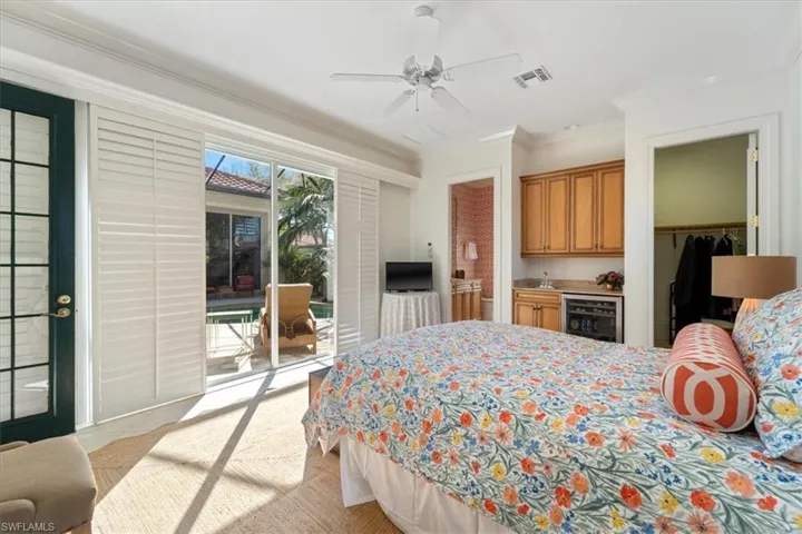 Bedroom featuring beverage cooler, indoor bar, visible vents, access to outside, and ornamental molding