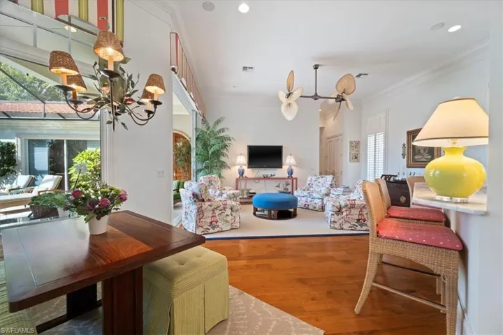 Living area featuring an inviting chandelier, visible vents, ornamental molding, and wood finished floors