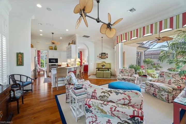 Living room with visible vents, crown molding, arched walkways, and a ceiling fan