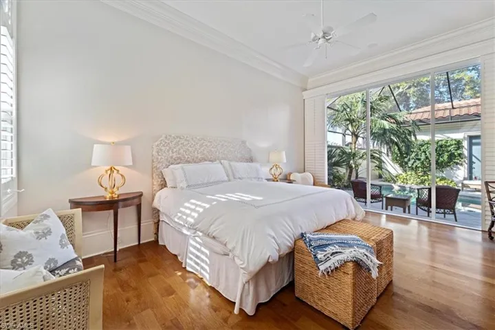 Bedroom featuring access to exterior, baseboards, crown molding, and wood finished floors