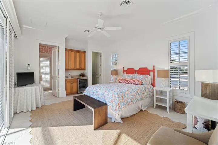 Bedroom with ornamental molding, wine cooler, visible vents, and light tile patterned floors