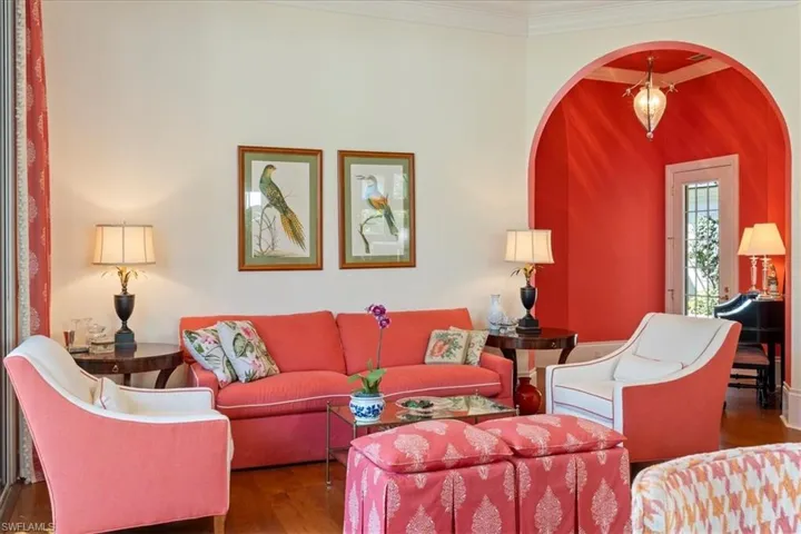 Living area with arched walkways, crown molding, and wood finished floors