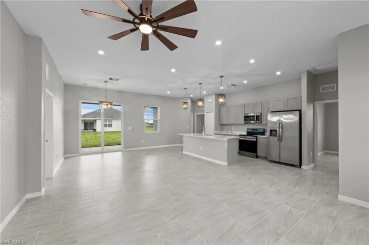Kitchen with recessed lighting, ceiling fan, gray cabinets, stainless steel appliances, and an island with sink