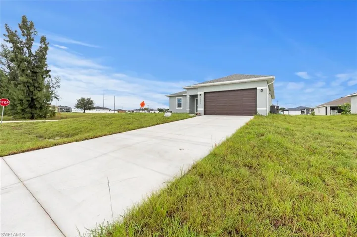 View of front of house featuring driveway, a front yard, an attached garage, and stucco siding