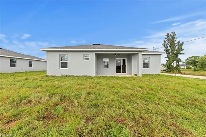 Rear view of house featuring a patio area, stucco siding, and a yard