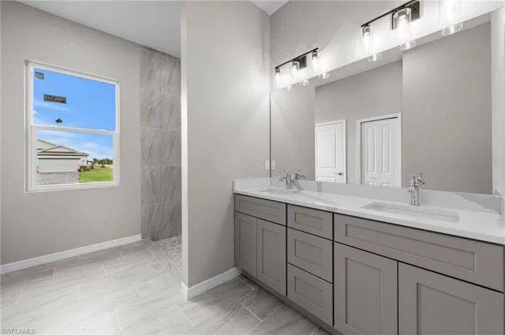 Full bathroom with double vanity and tiled shower