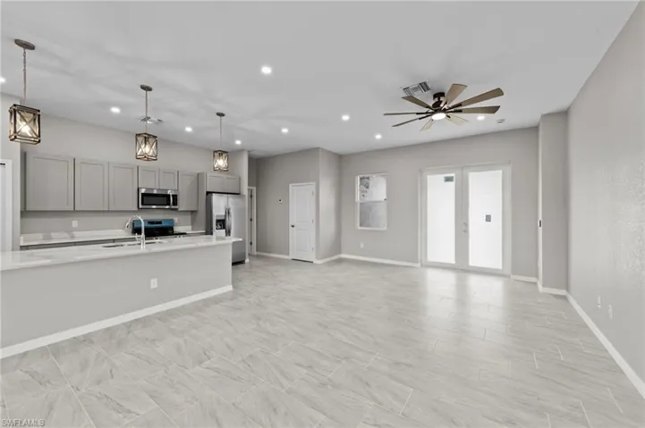 Kitchen with gray cabinetry, open floor plan, appliances with stainless steel finishes, pendant lighting, and french doors