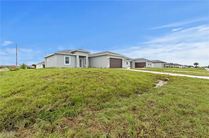 Single story home featuring an attached garage, stucco siding, a front lawn, and driveway