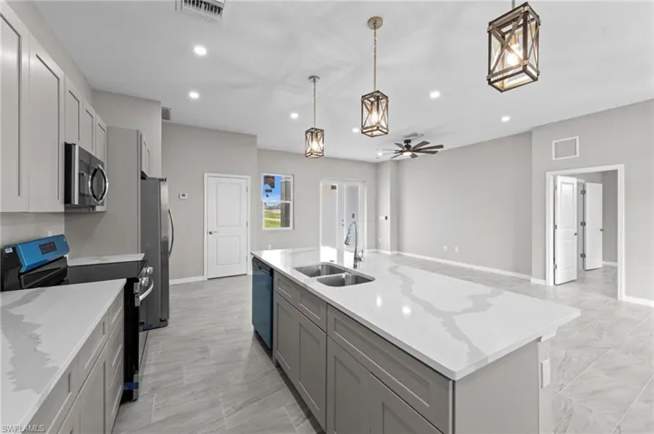 Kitchen featuring appliances with stainless steel finishes, ceiling fan, decorative light fixtures, recessed lighting, and a kitchen island with sink