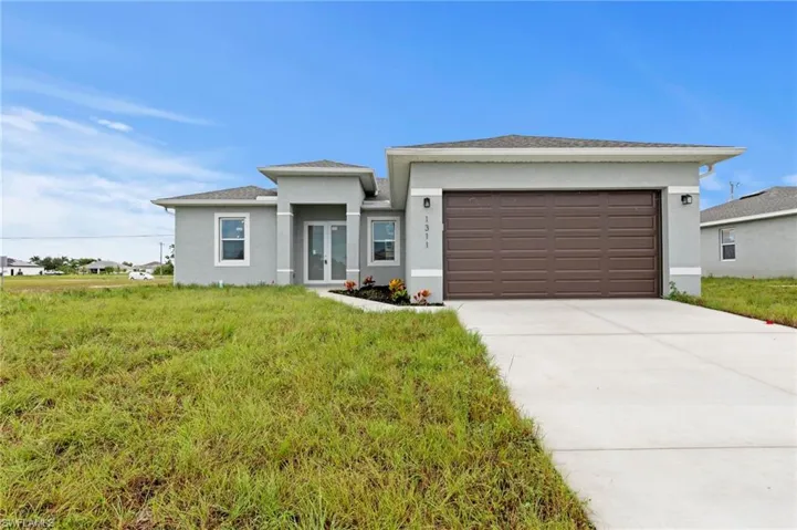 Prairie-style home with stucco siding, concrete driveway, an attached garage, and french doors