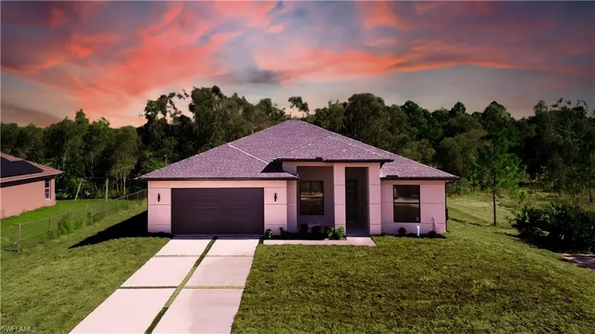 View of front of property featuring concrete driveway, stucco siding, an attached garage, and roof with shingles