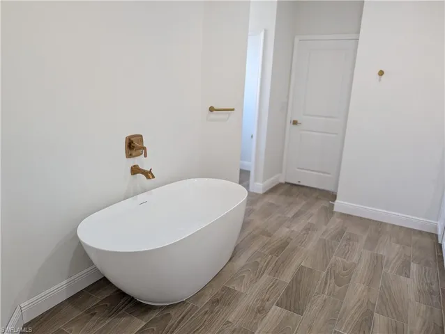 Full bath featuring wood tiled floors and a freestanding tub