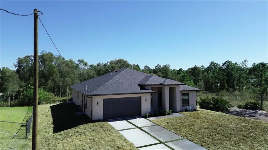 View of front facade with a shingled roof, stucco siding, an attached garage, and driveway
