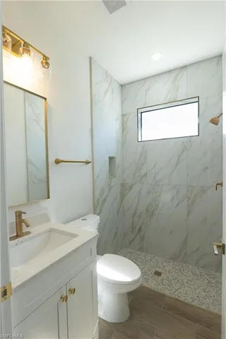 Bathroom featuring vanity and a marble finish shower