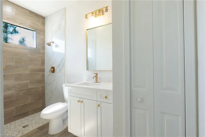 Full bath featuring a closet, vanity, tiled shower, and wood tiled floors