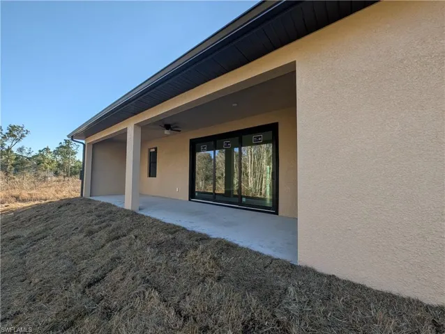 Entrance to property with stucco siding, a patio, and a ceiling fan