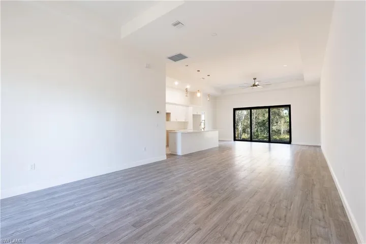 Unfurnished living room featuring light wood-style floors, a raised ceiling, and ceiling fan