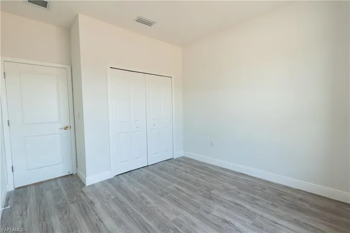 Unfurnished bedroom with wood finished floors and a closet