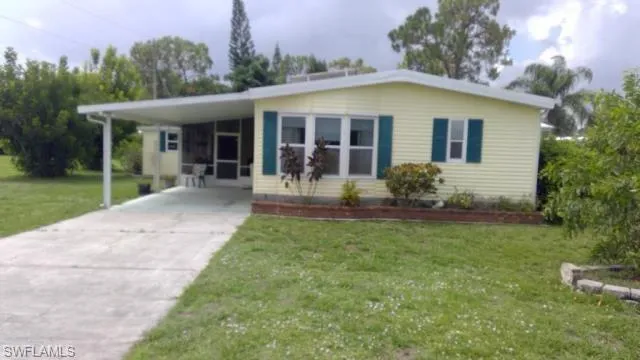 View of front of house with a carport and a front lawn