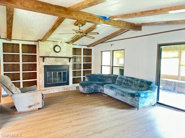 Spacious living room featuring lofted ceiling with beams, a gas fireplace, ceiling fan,