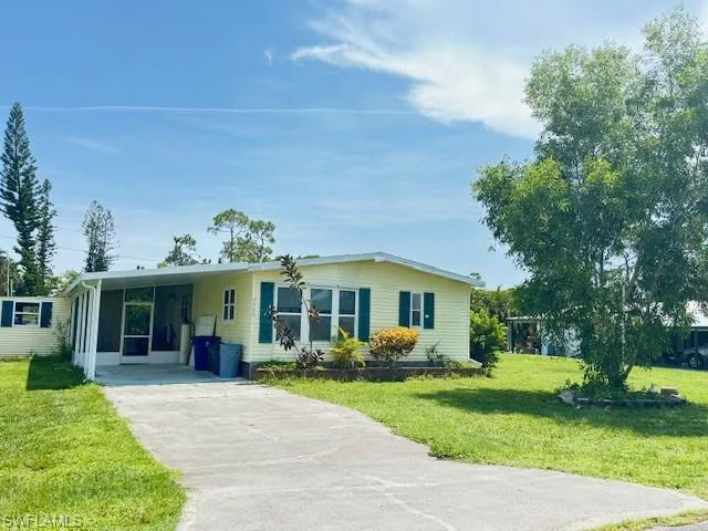 View of front of property featuring a front lawn and a carport