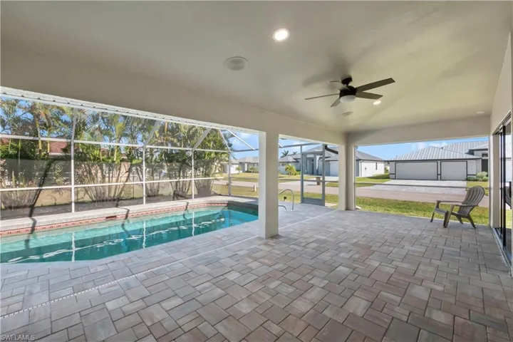 View of swimming pool featuring glass enclosure, ceiling fan, and a patio