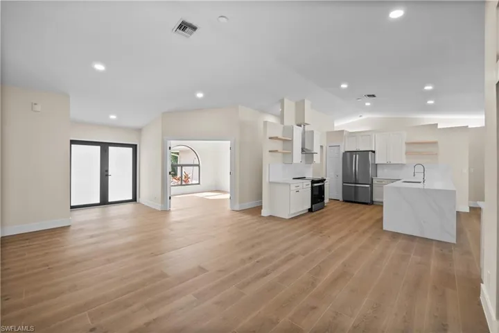 Kitchen featuring white cabinetry, sink, light hardwood / wood-style flooring, lofted ceiling, and appliances with stainless steel finishes