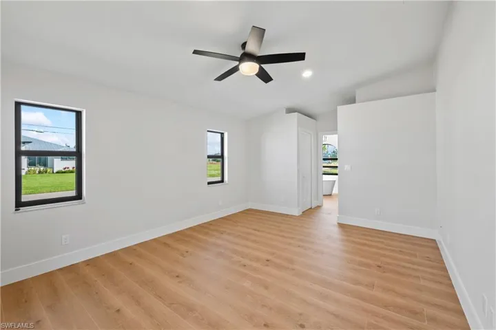 Empty room with ceiling fan, plenty of natural light, vaulted ceiling, and light wood-type flooring