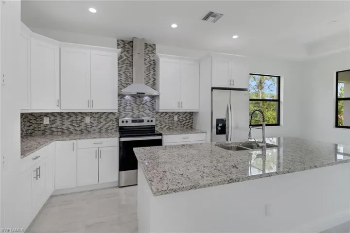 Kitchen featuring a center island, lost of storage and a range hood.
