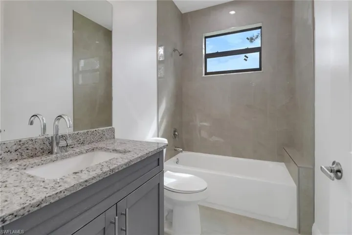 Full bathroom featuring vanity, tiled shower / bath combo, and toilet