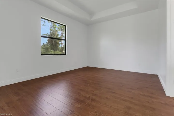 Master bedroom, with dark Laminate style floors and a tray ceiling.