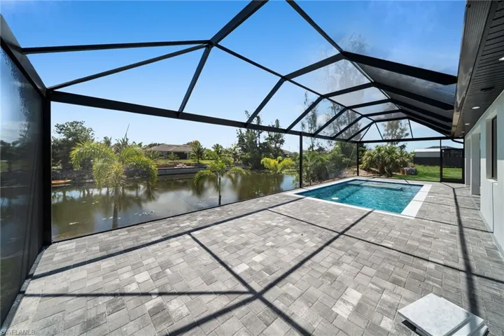 Swimming pool with a patio, a water view, and a lanai