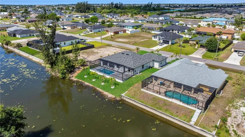 Aerial perspective of suburban area featuring a pool area and a large body of water