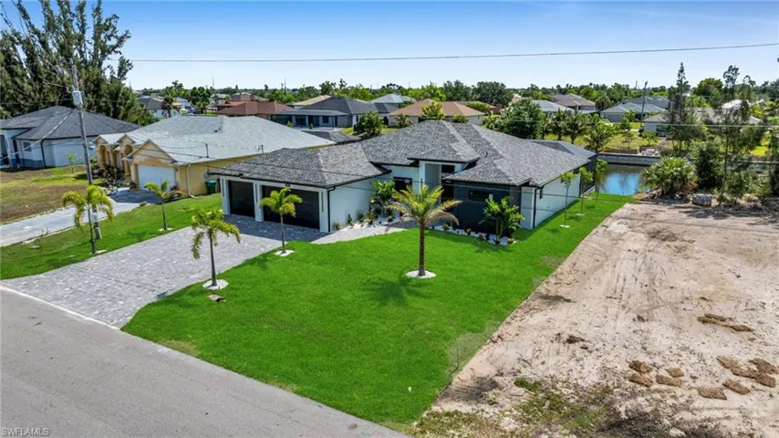 Ranch-style house featuring decorative driveway, a residential view, an attached garage, a front lawn, and roof with shingles