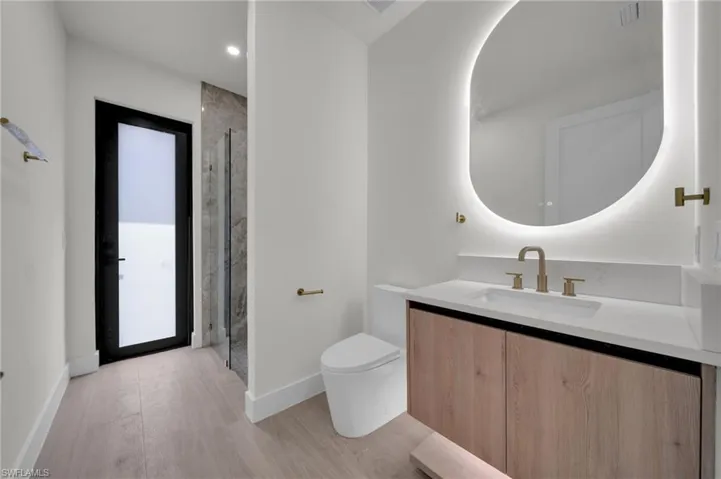 Full bathroom with toilet, wood finished floors, vanity, walk in shower, and recessed lighting