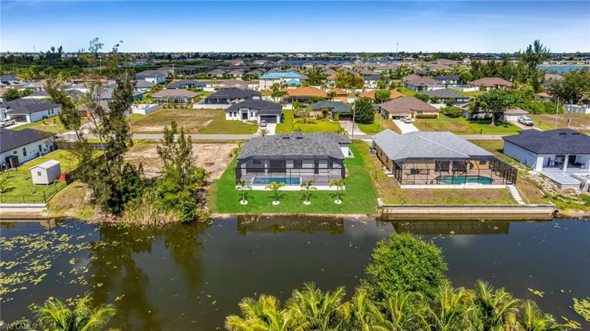 Aerial view of residential area featuring a nearby body of water and a pool area