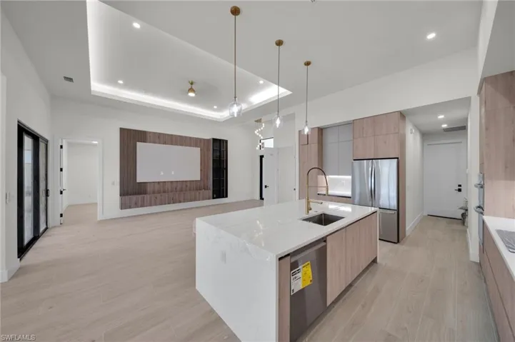 Kitchen with modern cabinets, appliances with stainless steel finishes, a sink, light wood-style floors, and a large island