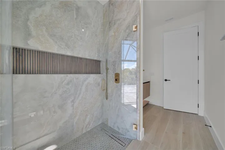 Bathroom with a stall shower, wood finished floors, and baseboards