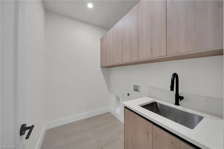 Laundry area with cabinet space, electric dryer hookup, hookup for a washing machine, baseboards, and recessed lighting