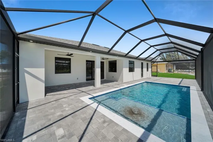 Swimming pool featuring a ceiling fan, a patio area, and glass enclosure