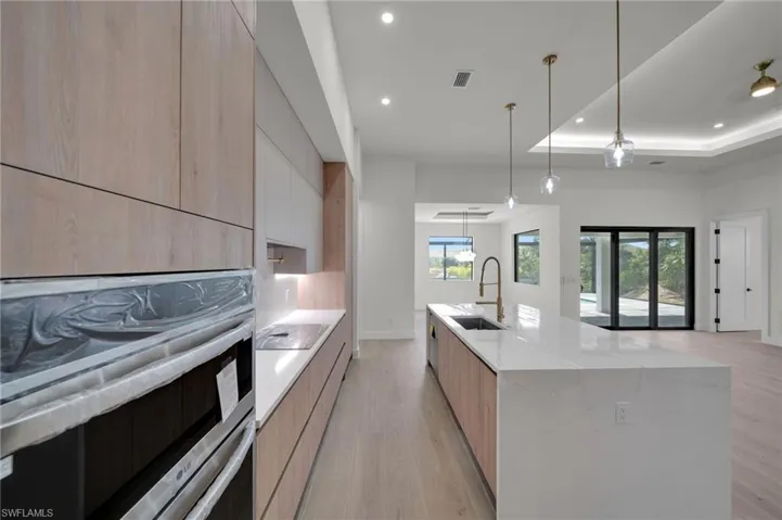Kitchen with modern cabinets, a sink, recessed lighting, light brown cabinets, and light wood-style flooring