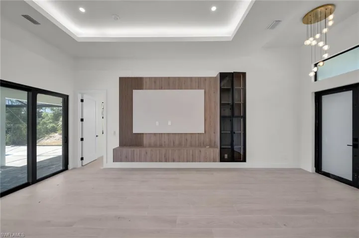 Foyer entrance with light wood finished floors, a tray ceiling, a chandelier, and recessed lighting