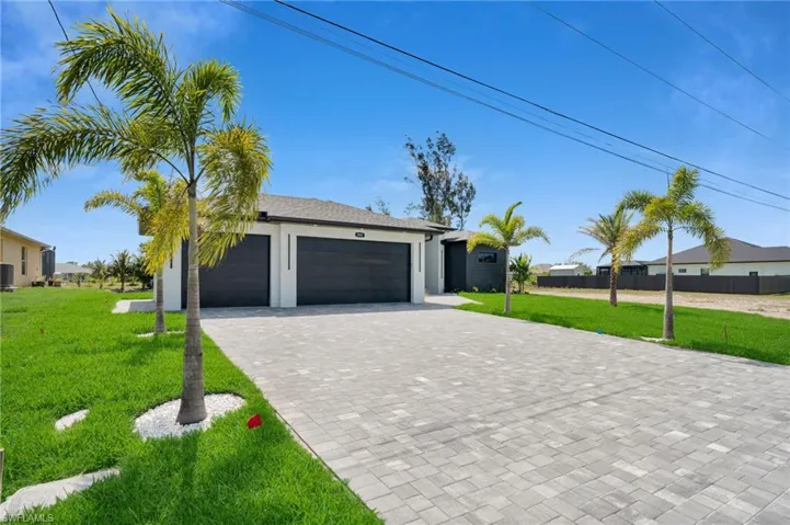 View of front facade featuring decorative driveway, an attached garage, stucco siding, and central air condition unit