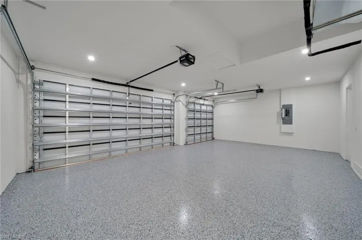 Garage featuring a garage door opener, recessed lighting, and electric panel