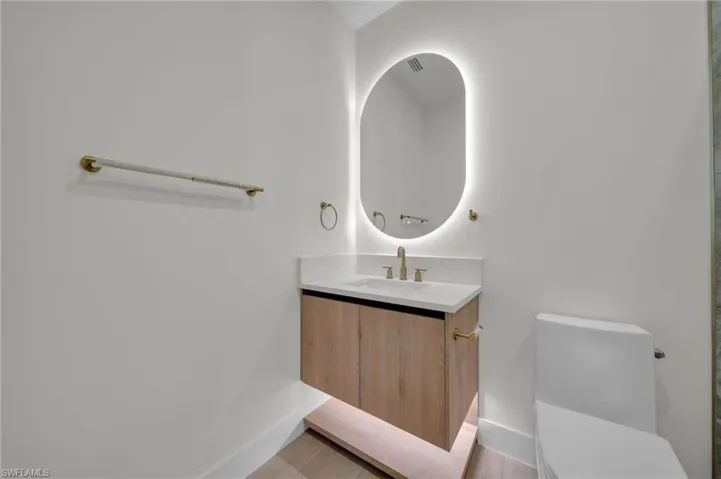 Bathroom with vanity, toilet, and baseboards
