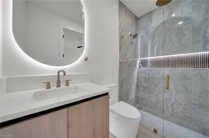 Bathroom with a stall shower, toilet, and vanity
