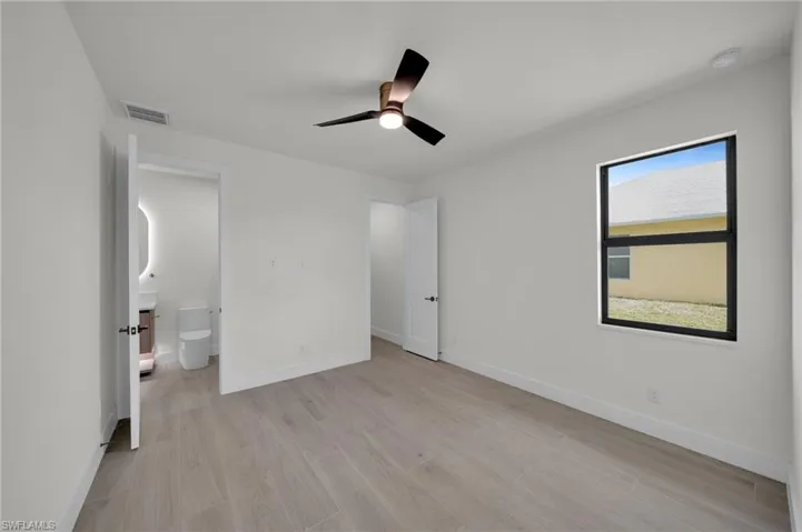 Unfurnished bedroom featuring light wood finished floors, baseboards, and connected bathroom
